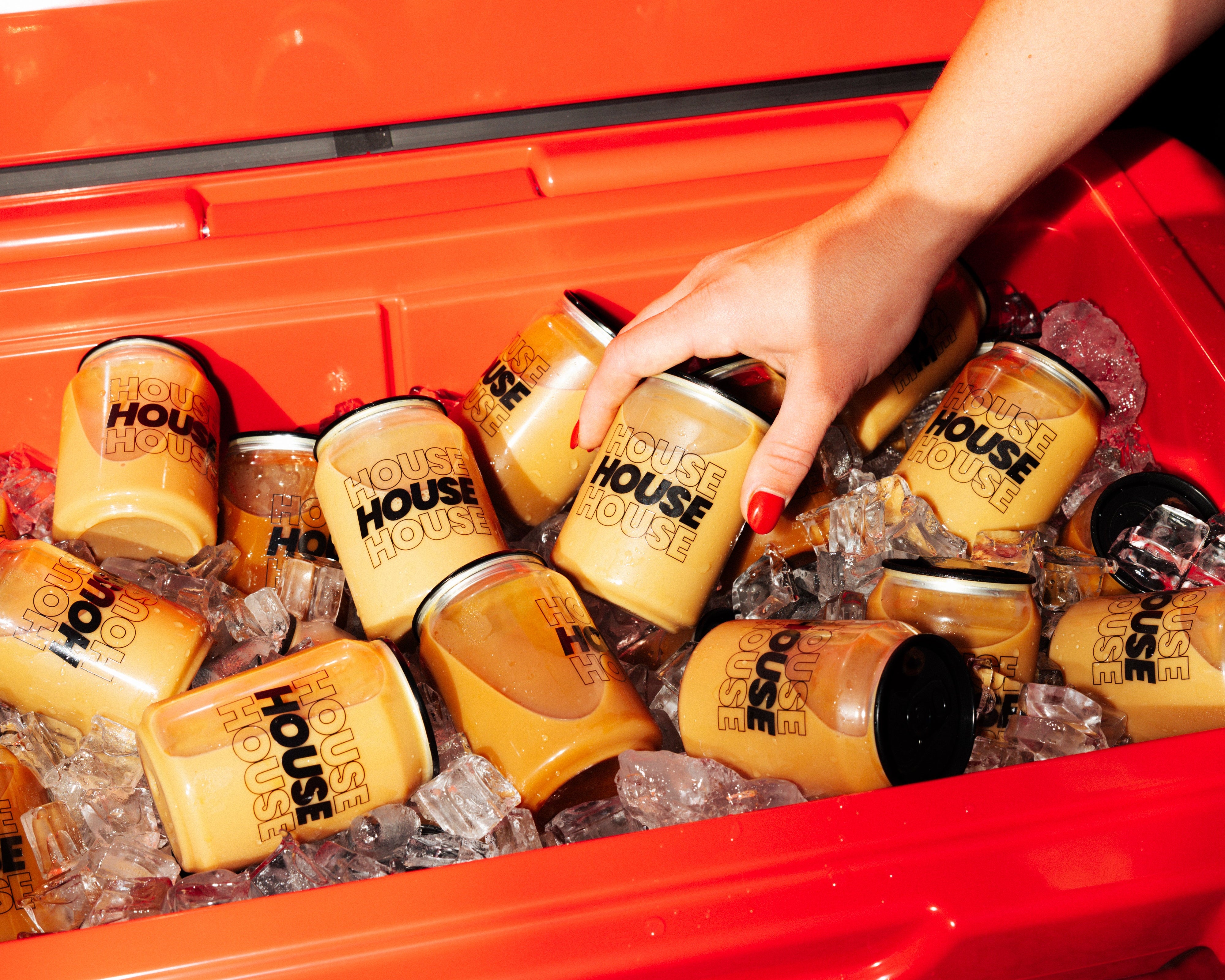 Event goer reaches into a red YETI cooler filled with ice, picking up a HOUSE can of Mini Cold Brew.